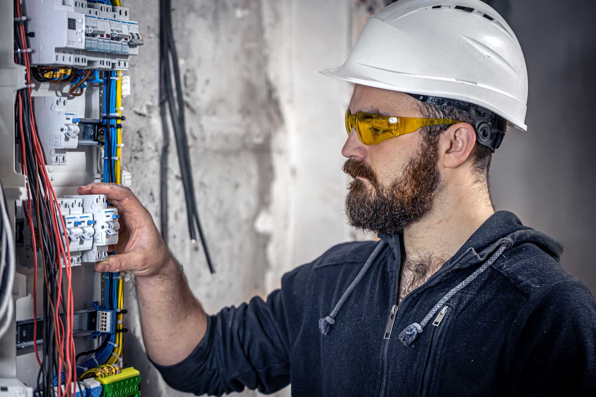 Image depicting a skilled male electrician focused on his work inside a switchboard, demonstrating expertise and professionalism.